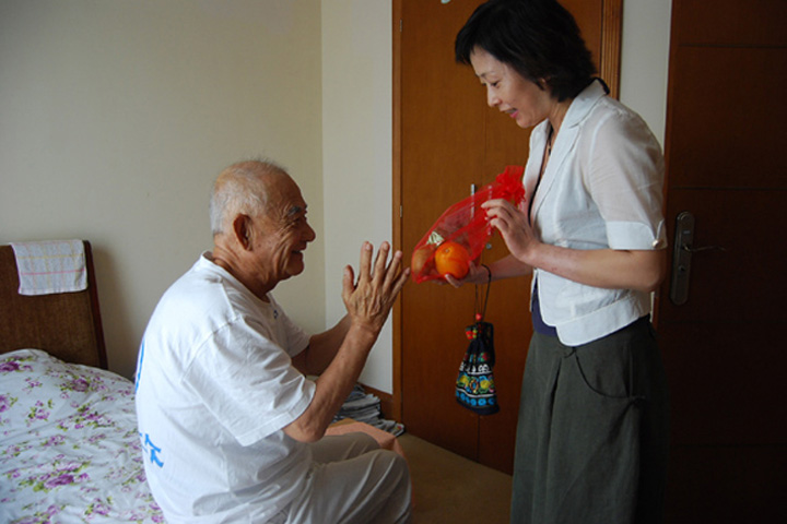 A YICT employee presents gifts to a senior and says Happy Festival and Good Health.